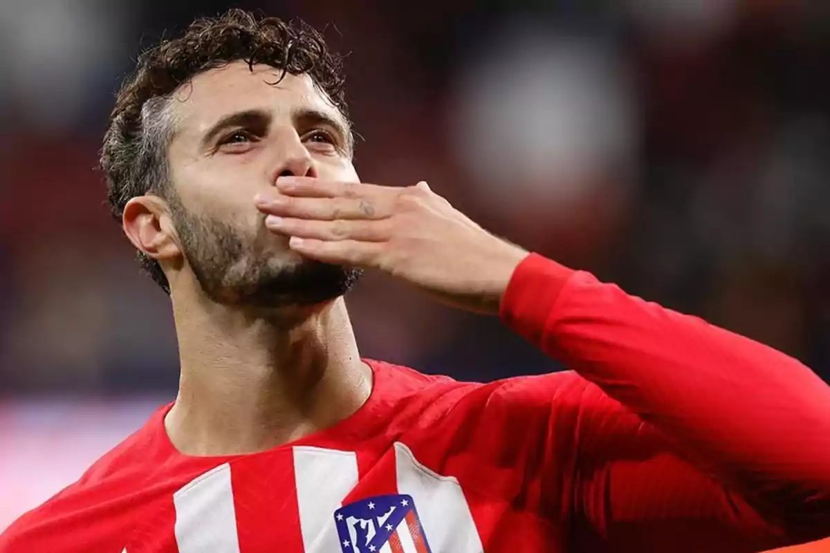 Un jugador de fútbol con la camiseta del Atlético de Madrid sopla un beso al aire.