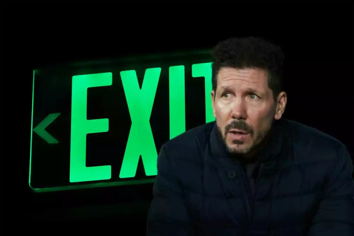 Hombre con chaqueta oscura frente a un letrero verde de "EXIT".