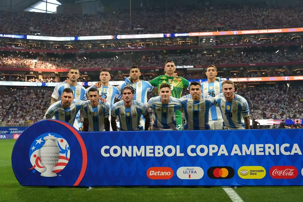 Jugadores de la selección argentina posando para una foto grupal antes de un partido de la CONMEBOL Copa América en un estadio lleno de espectadores.
