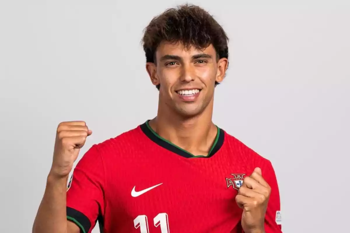 Un jugador de fútbol con la camiseta roja de la selección de Portugal, levantando ambos puños en señal de celebración.