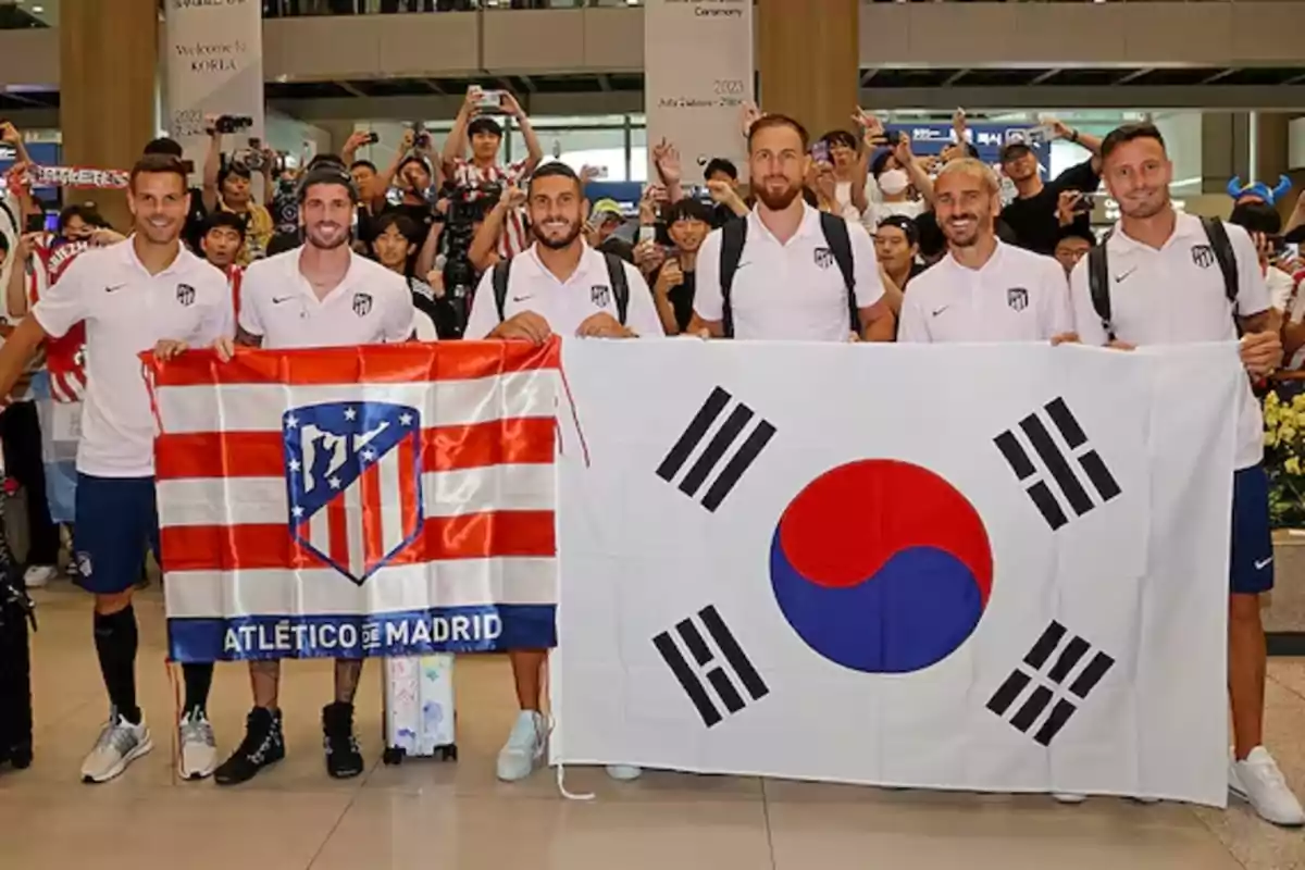 Jugadores del Atlético de Madrid posan con una bandera del equipo y una bandera de Corea del Sur en un evento de bienvenida en Corea.